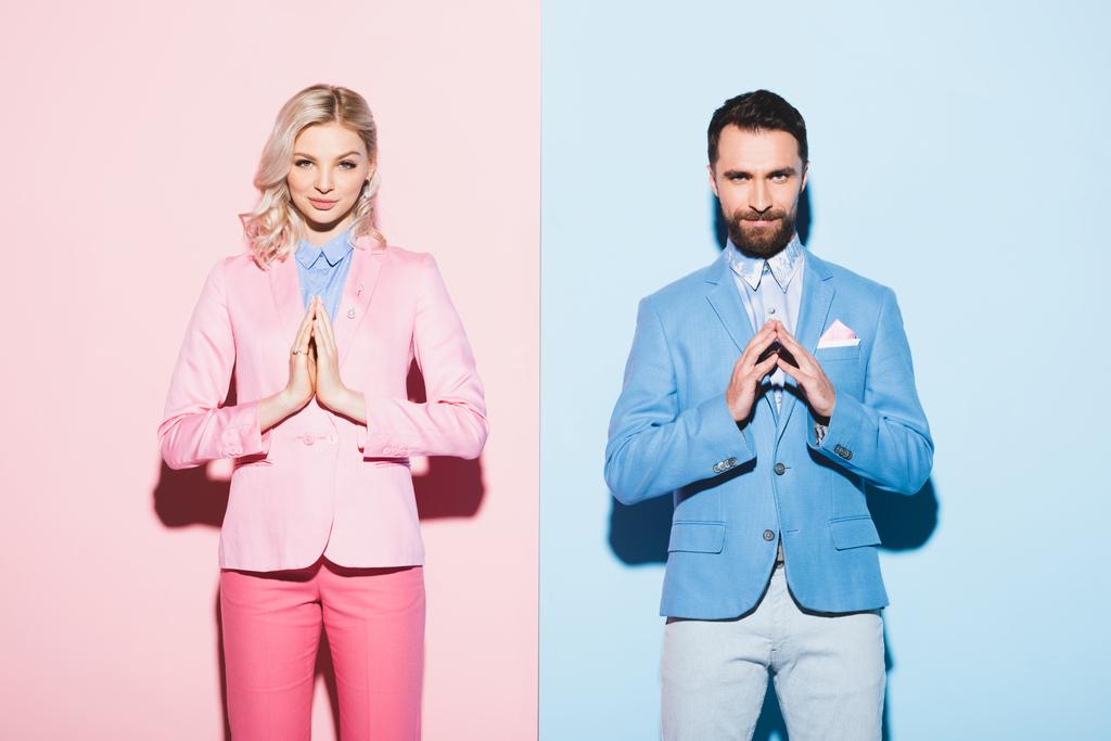 attractive woman and smiling man with praying hands on pink and blue background  - Photo, Image