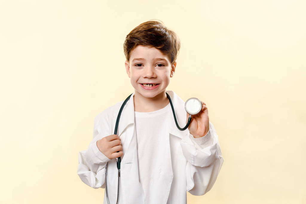 可愛い未来の医者白い背景の上に。少年は医者を演じる。子供向けゲームです医者さん白いコートとフォノ内視鏡スタジオでの感情的な赤ん坊 - 写真・画像