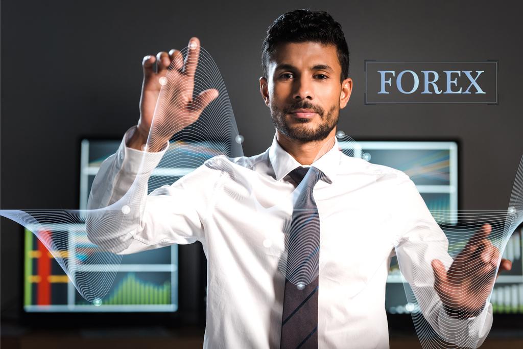 selektywne skupienie się na dwurasowym przedsiębiorcy wskazującym palcami w pobliżu komputerów i liter forex - Zdjęcie, obraz