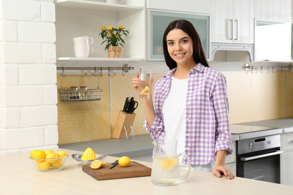 Bella giovane donna con acqua di limone in cucina
 - Foto, immagini