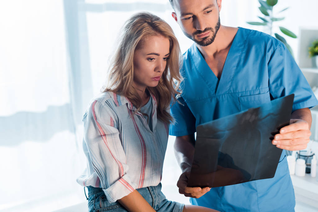 handsome orthopedist and attractive woman looking at x-ray  - Photo, Image