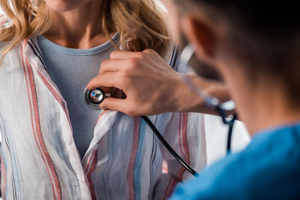 oříznutý pohled na lékaře držícího stetoskop při vyšetření ženy  - Fotografie, Obrázek