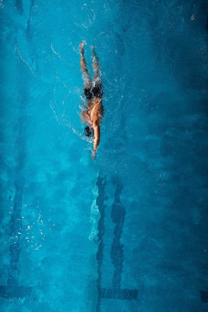 ylhäältä näkymä urheilija uinti edessä indeksoida sinisellä vedellä
  - Valokuva, kuva