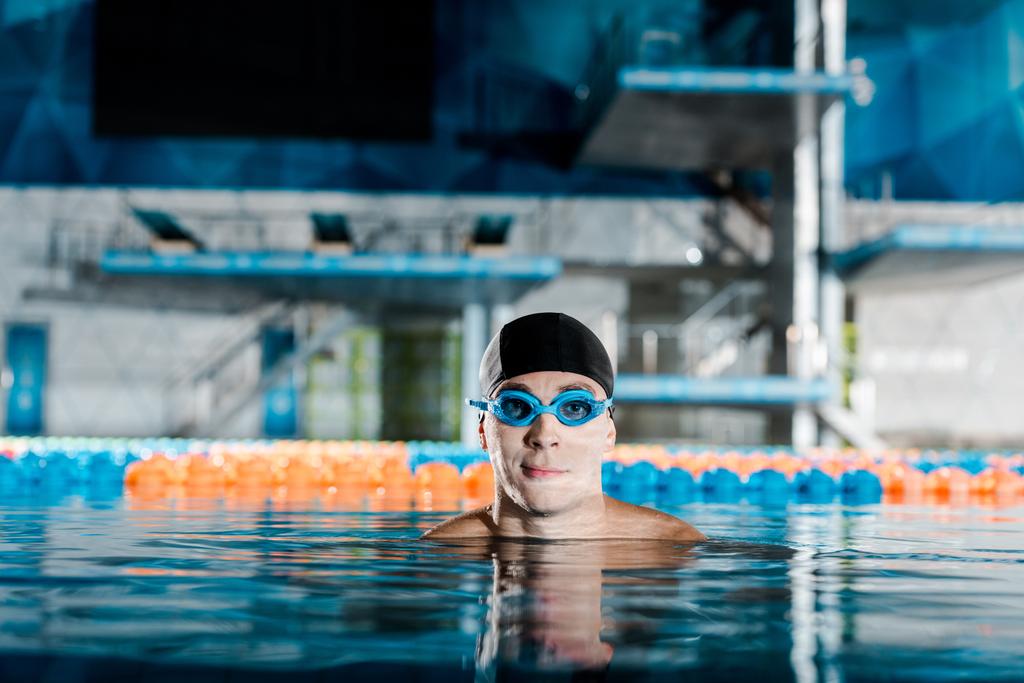 nadador em óculos e touca de natação olhando para a câmera
  - Foto, Imagem