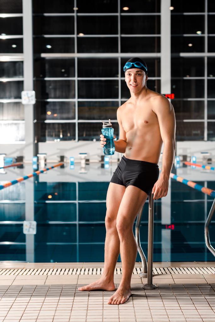 szczęśliwy pływak stojący i trzymający butelkę sportową  - Zdjęcie, obraz