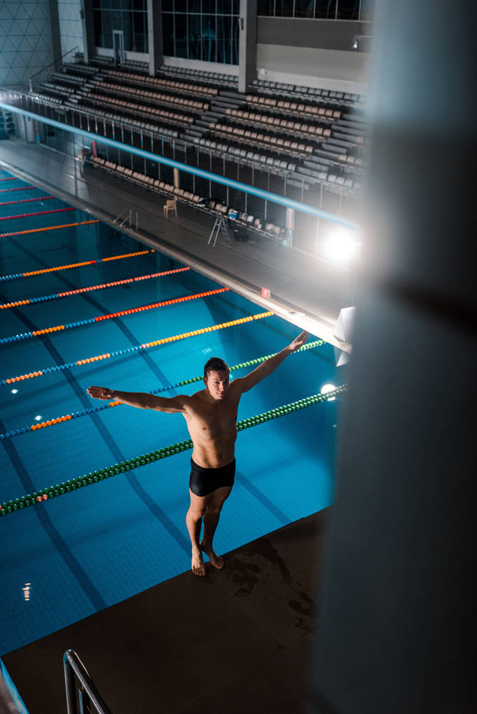 vista de alto ângulo do nadador de pé com as mãos acima da cabeça perto da piscina
  - Foto, Imagem