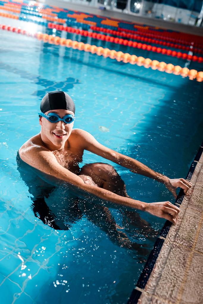 nadador feliz em óculos sorrindo enquanto olha para a câmera na piscina
  - Foto, Imagem