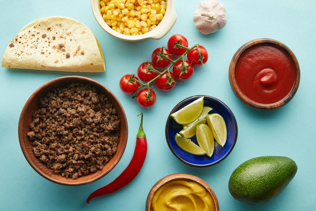 Vue du dessus des ingrédients frais pour taco avec viande sur fond bleu
 - Photo, image