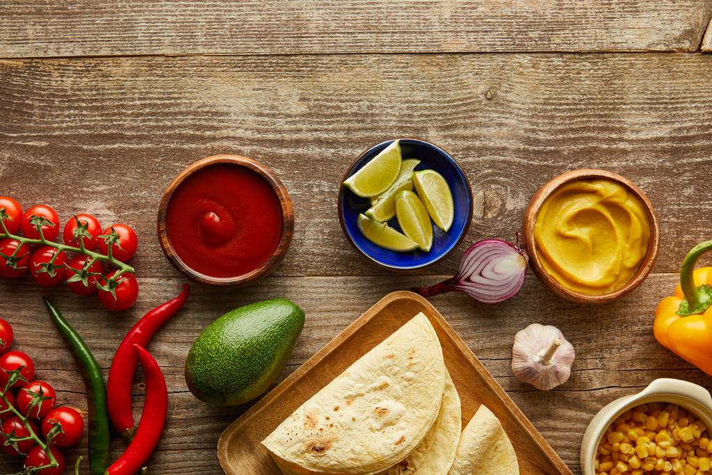 Bovenaanzicht van rijpe ingrediënten voor taco 's op houten ondergrond - Foto, afbeelding