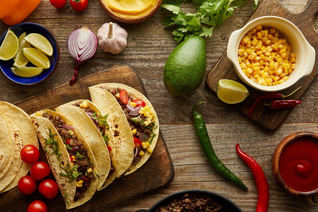 Top view of traditional mexican tacos with organic ingredients on wooden background - 写真・画像