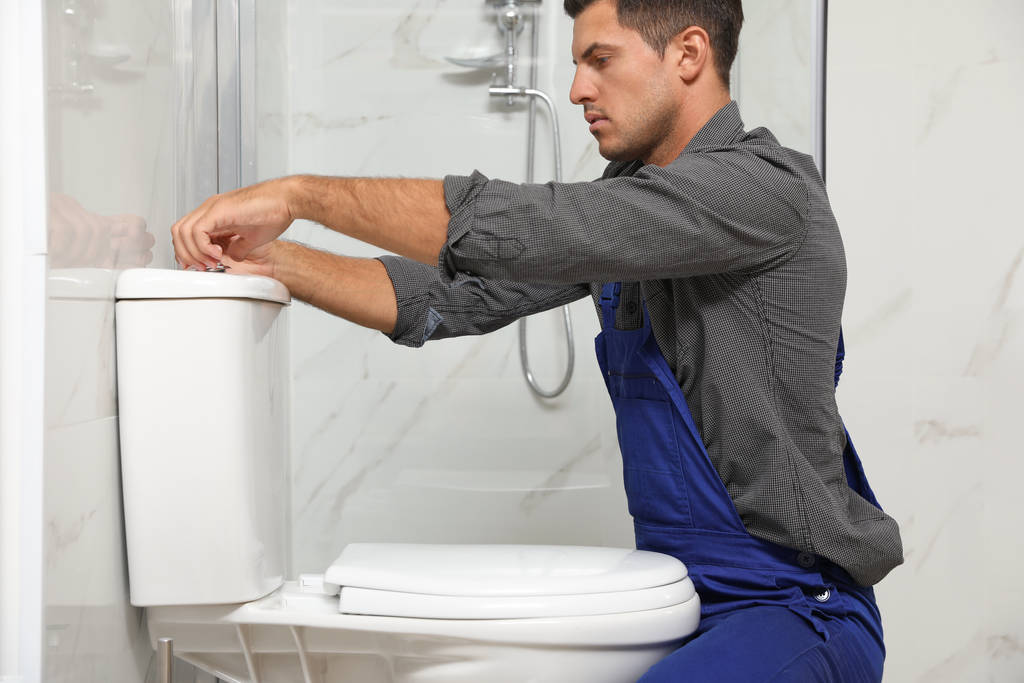 fontanero profesional trabajando con inodoro en el baño
 - Foto, imagen