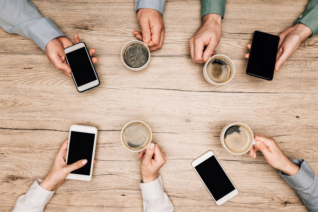 Vista superior de pessoas de negócios bebendo café e usando smartphones na mesa de madeira, vista cortada
 - Foto, Imagem