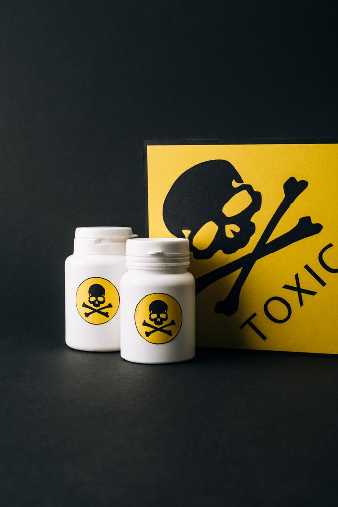 Jars and card with toxic sign isolated on black - Photo, Image