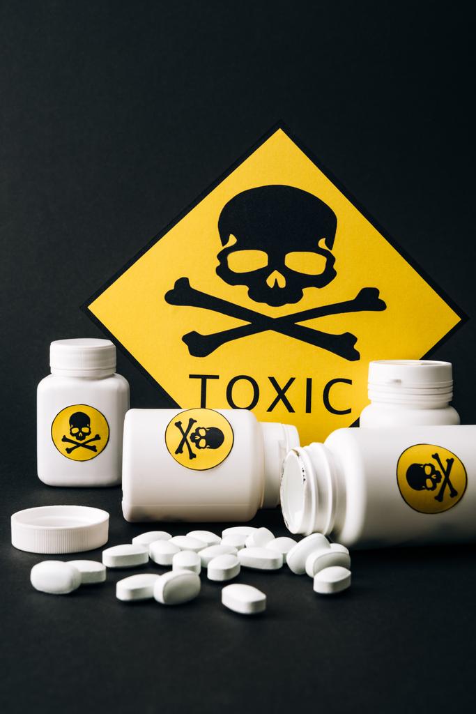 Toxic sign with jars and pills isolated on black - Photo, Image