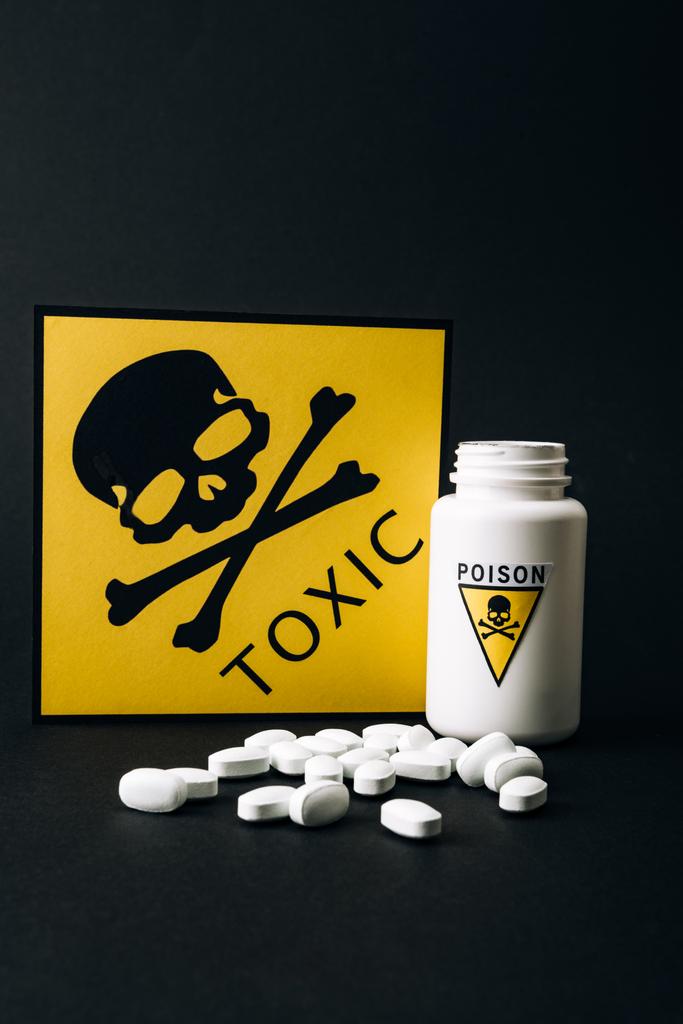 Prášky v láhvi s jedem znamení a karta s toxickým symbolem izolované na černé - Fotografie, Obrázek
