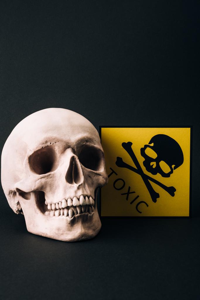 Schedel en geel giftig teken geïsoleerd op zwart - Foto, afbeelding