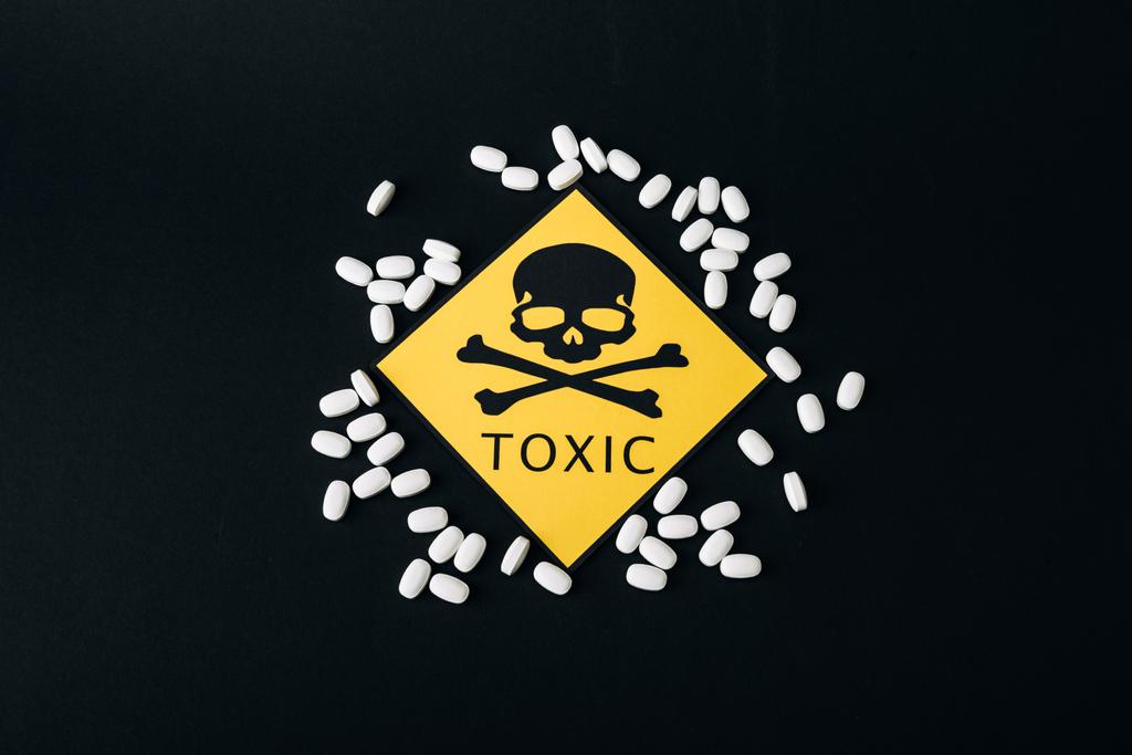 Top view of pills and toxic sign isolated on black - Photo, Image