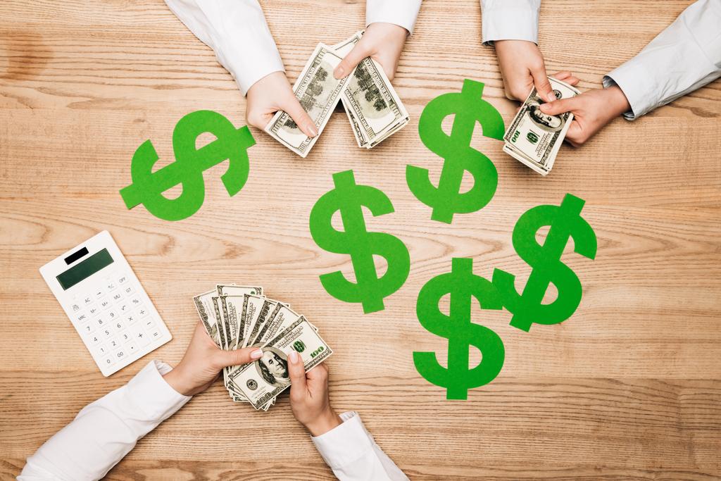 Топ-просмотр бизнес-партнеров, держащих наличные деньги рядом с калькулятором и долларовыми таблицами
 - Фото, изображение