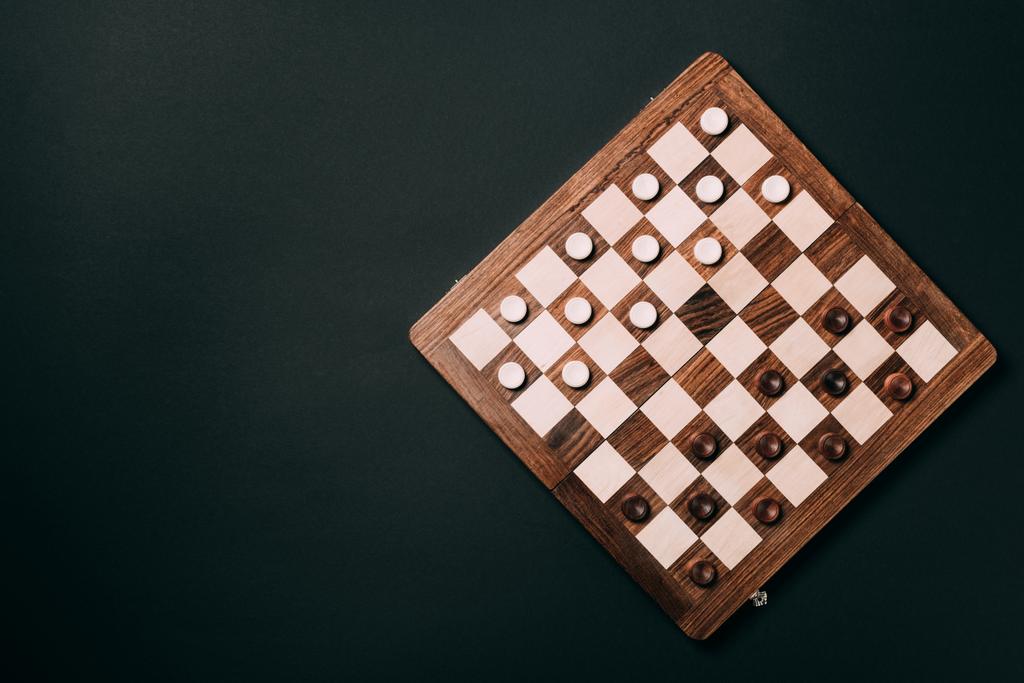 Vista superior de tablero de ajedrez de madera con damas aisladas en negro
 - Foto, imagen