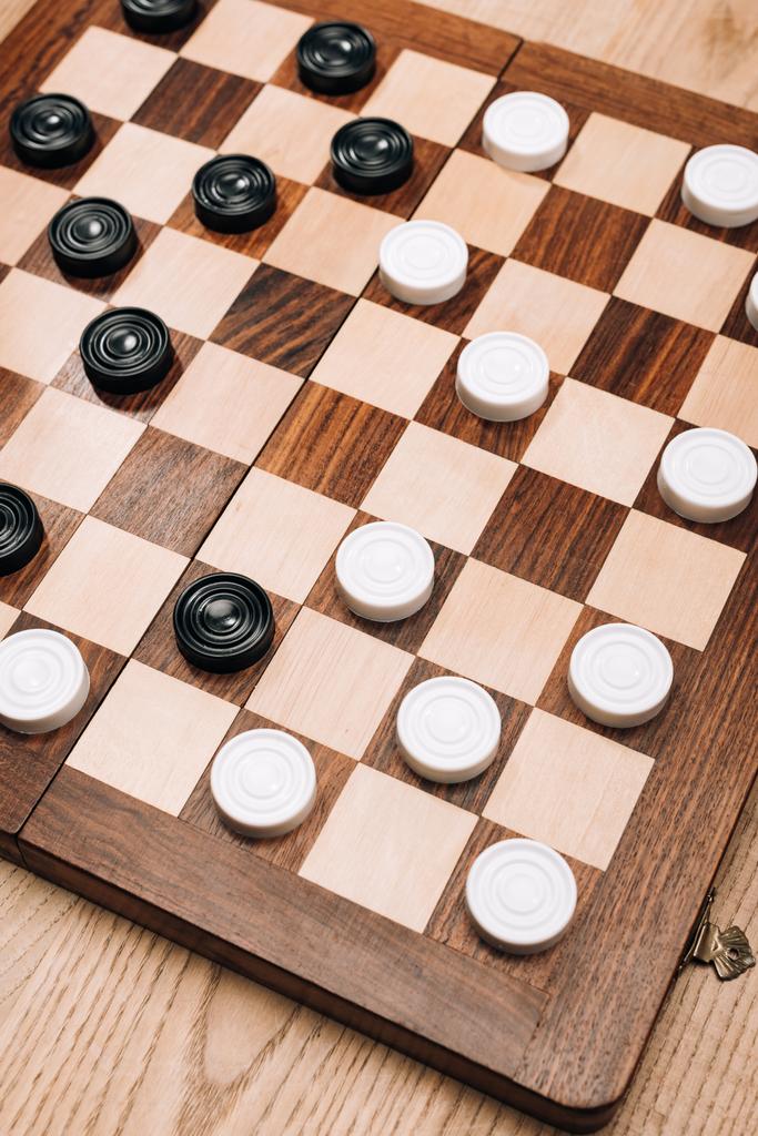 High angle view of checkers on checkerboard on wooden table - Photo, Image