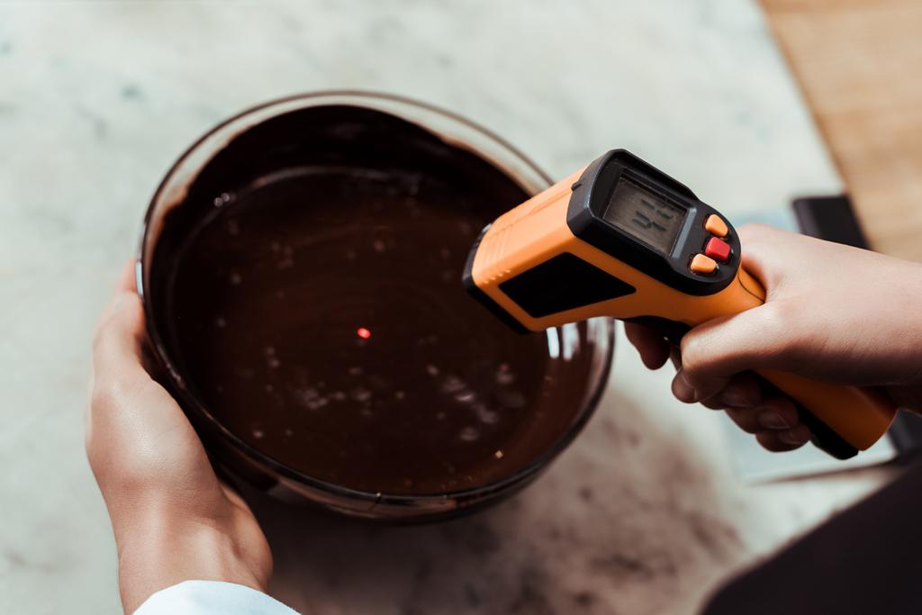 vista cortada de chocolate segurando termômetro de cozinha perto da tigela com chocolate escuro
  - Foto, Imagem