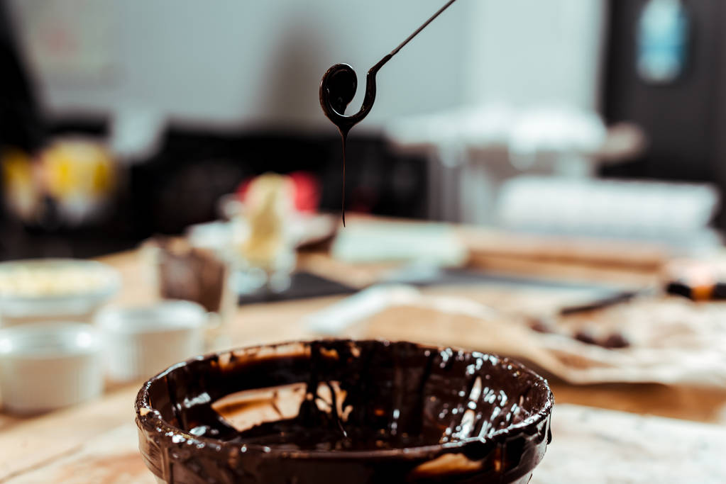 foco seletivo de redemoinho batedor com gotas de chocolate derretido perto tigela
  - Foto, Imagem