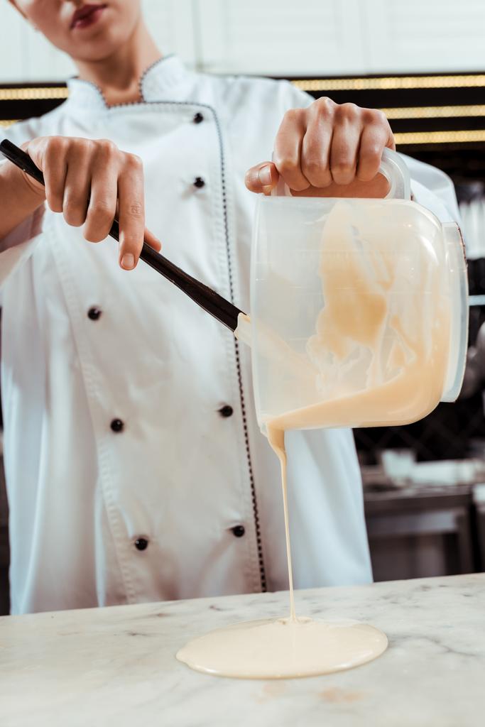 cropped view of chocolatier pouring melted white chocolate on marble surface  - Photo, Image