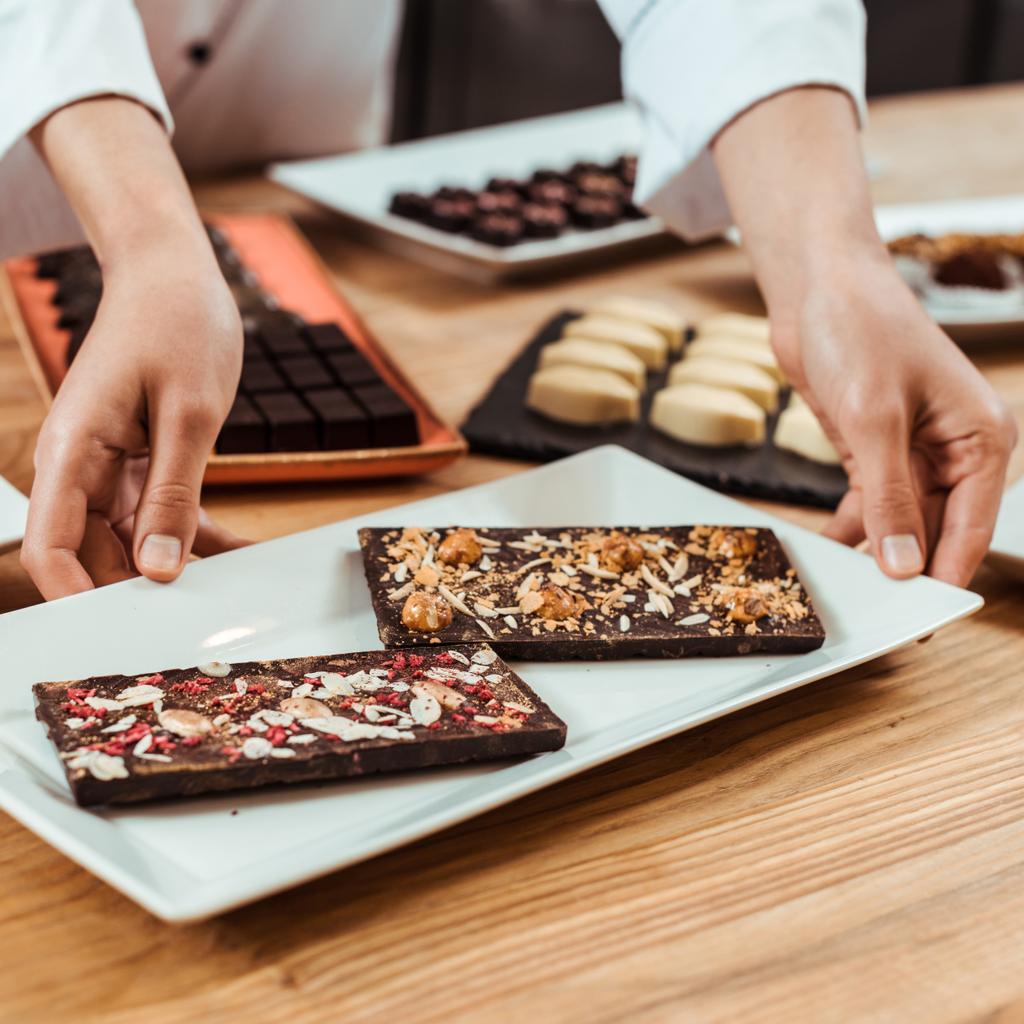 cropped view of woman touching plate with fresh prepared chocolate bars  - Photo, Image