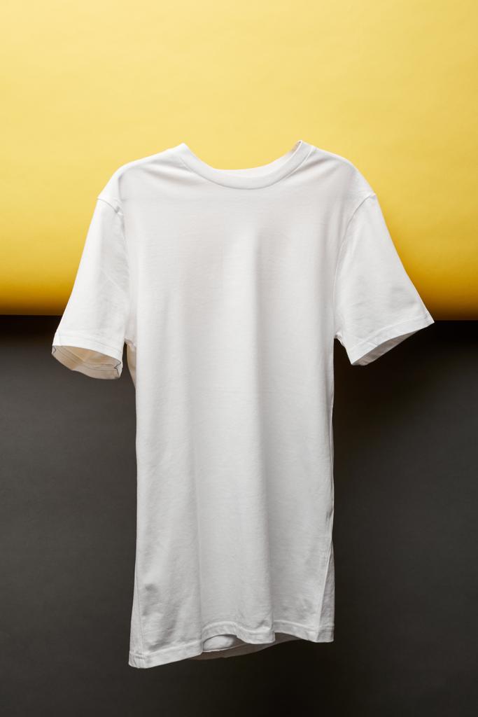 blanco basic wit t-shirt op zwarte en gele achtergrond - Foto, afbeelding