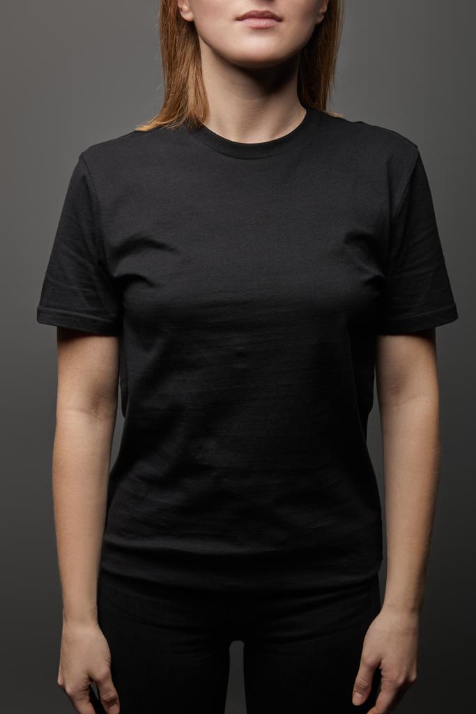 cropped view of woman in blank basic black t-shirt on black background - Photo, Image