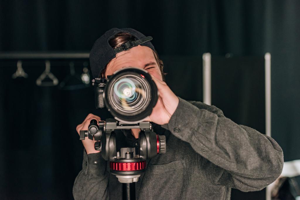 Видеограф, смотрящий в камеру во время работы в фотостудии
 - Фото, изображение