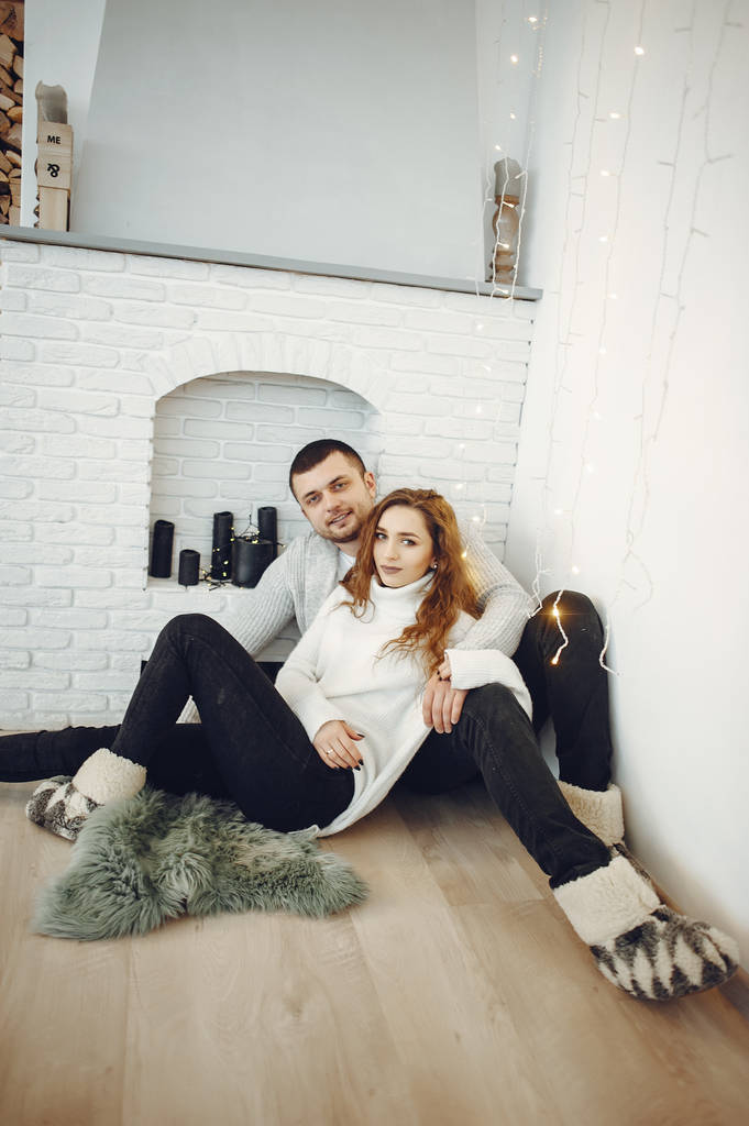 Χαριτωμένο ζευγάρι στο σπίτι με ζεστά πουλόβερ - Φωτογραφία, εικόνα