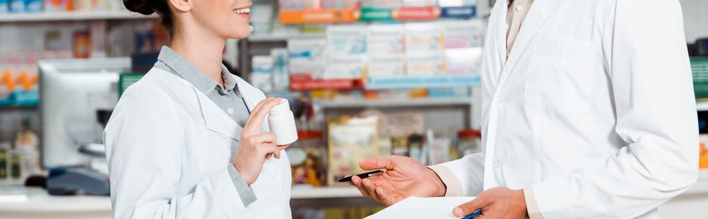 Oříznutý pohled lékárníků se schránkou a pilulkami v lékárně - Fotografie, Obrázek
