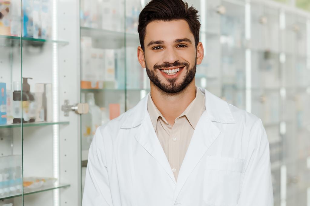 Όμορφος φαρμακοποιός χαμογελά στην κάμερα από βιτρίνα φαρμακείο - Φωτογραφία, εικόνα