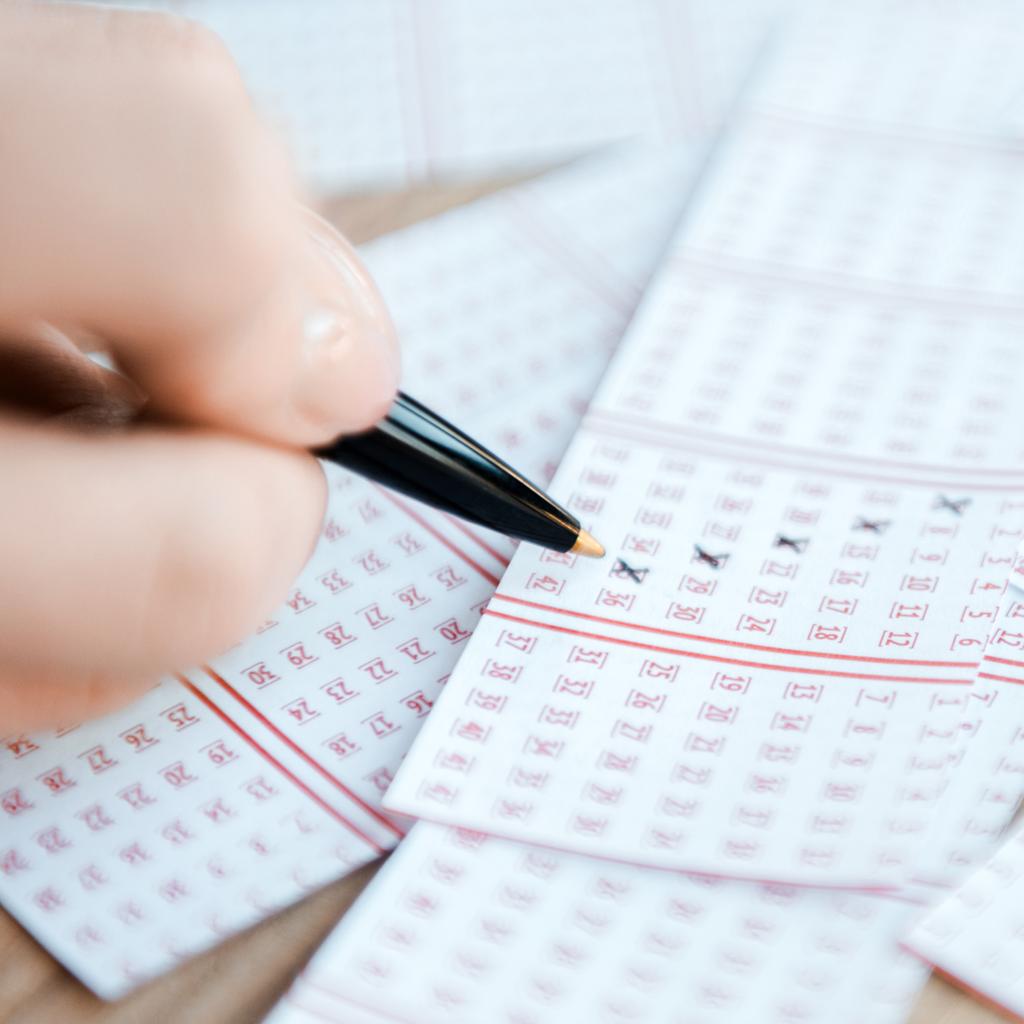 крупным планом женщин, маркирующих номера на лотерейных билетах на столе
 - Фото, изображение