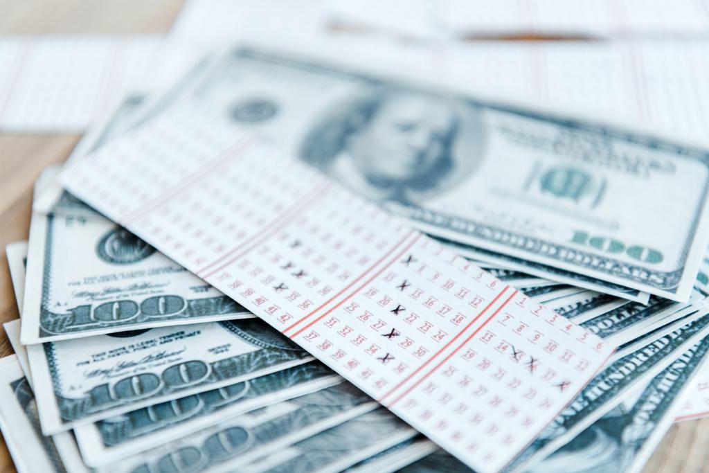 valikoiva painopiste merkitty arpalippu lähellä dollarin seteleitä pöydällä
 - Valokuva, kuva