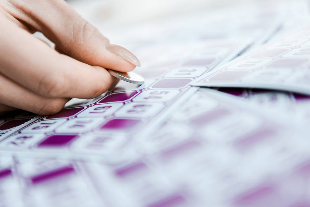 Selektiver Fokus der Frau mit Münze und zerkratztem Lottoschein  - Foto, Bild