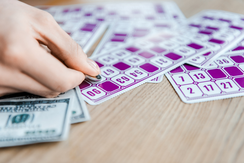 vista cortada de mulher segurando moeda e riscando bilhete de loteria perto de dinheiro
  - Foto, Imagem