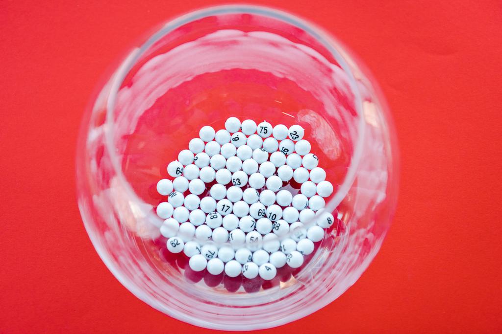 top view of glass bowl with lottery balls isolated on red - Photo, Image