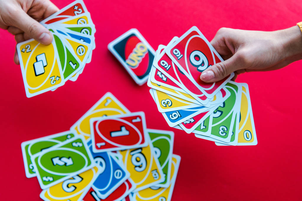 QUIIV, UCRÂNIA - NOVEMBRO 22, 2019: visão superior de amigos jogando uno jogando cartas isoladas em vermelho
  - Foto, Imagem