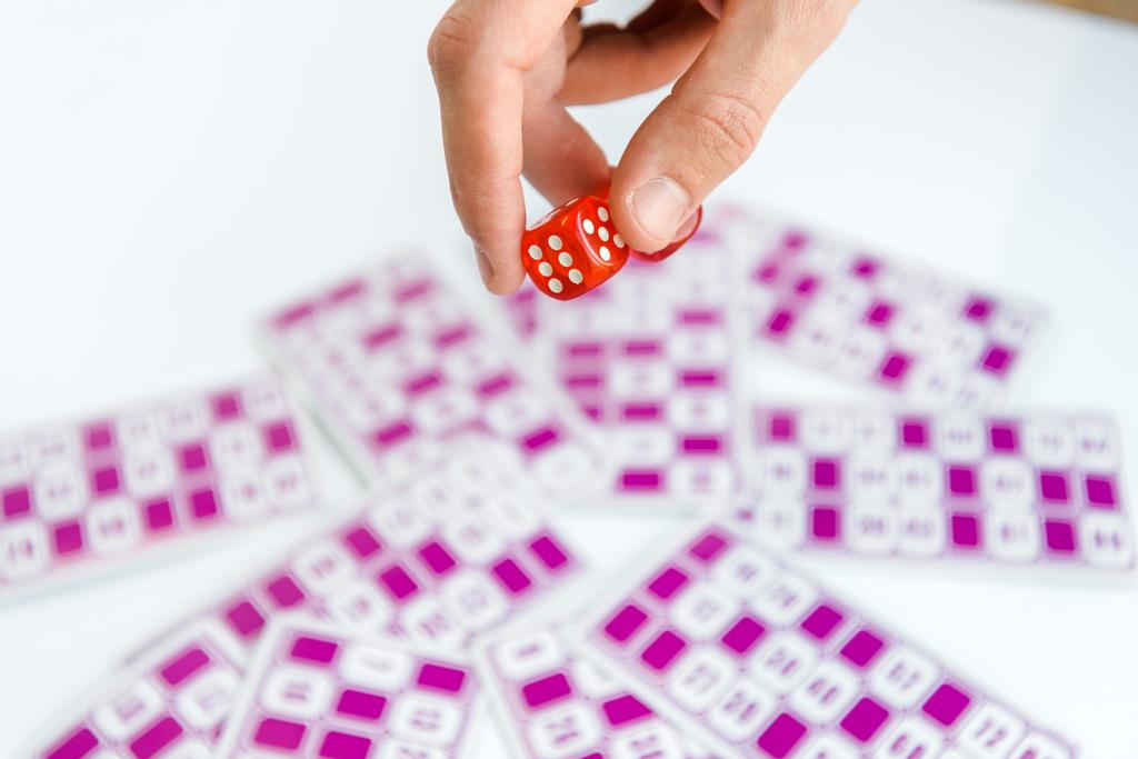 обрізаний вид людини, що тримає червоні кубики біля лотерейних квитків ізольовані на білому
  - Фото, зображення