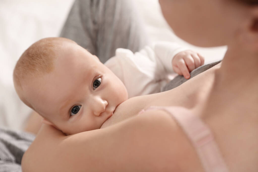 Молодая женщина кормит грудью своего малыша, вид сверху
 - Фото, изображение