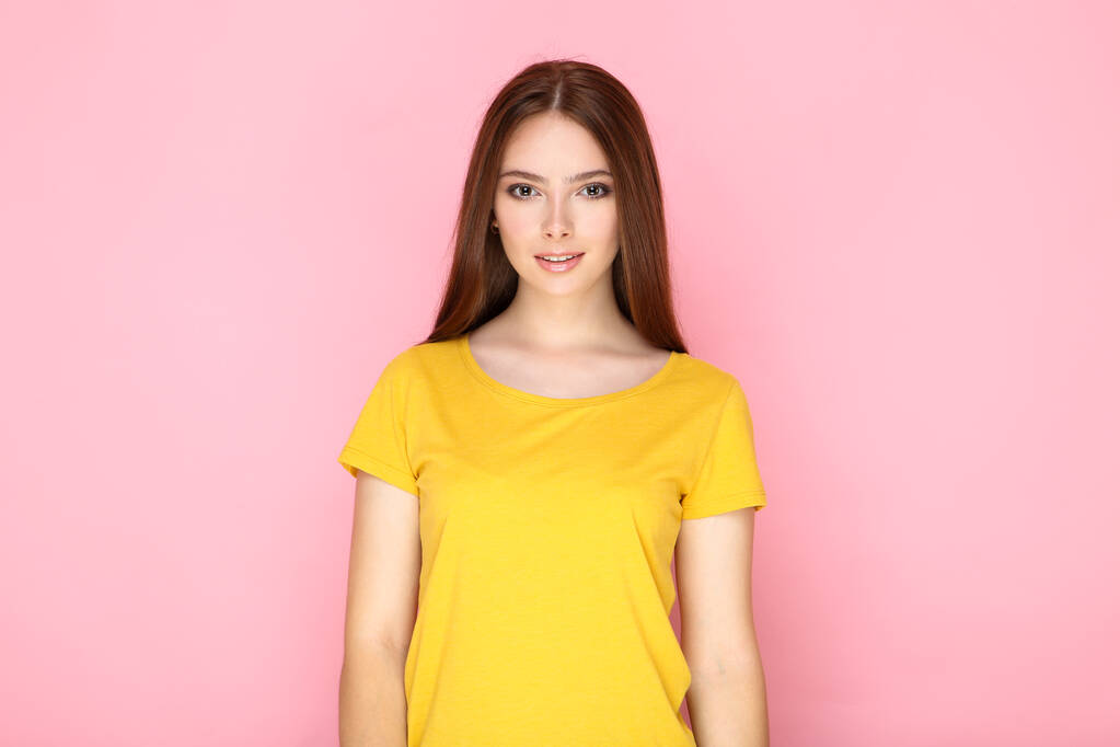 Νεαρή γυναίκα με κίτρινο t-shirt σε ροζ φόντο - Φωτογραφία, εικόνα