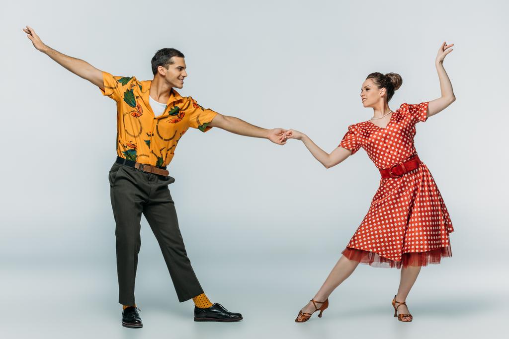 elegant dancers holding hands while dancing boogie-woogie on grey background - Photo, Image