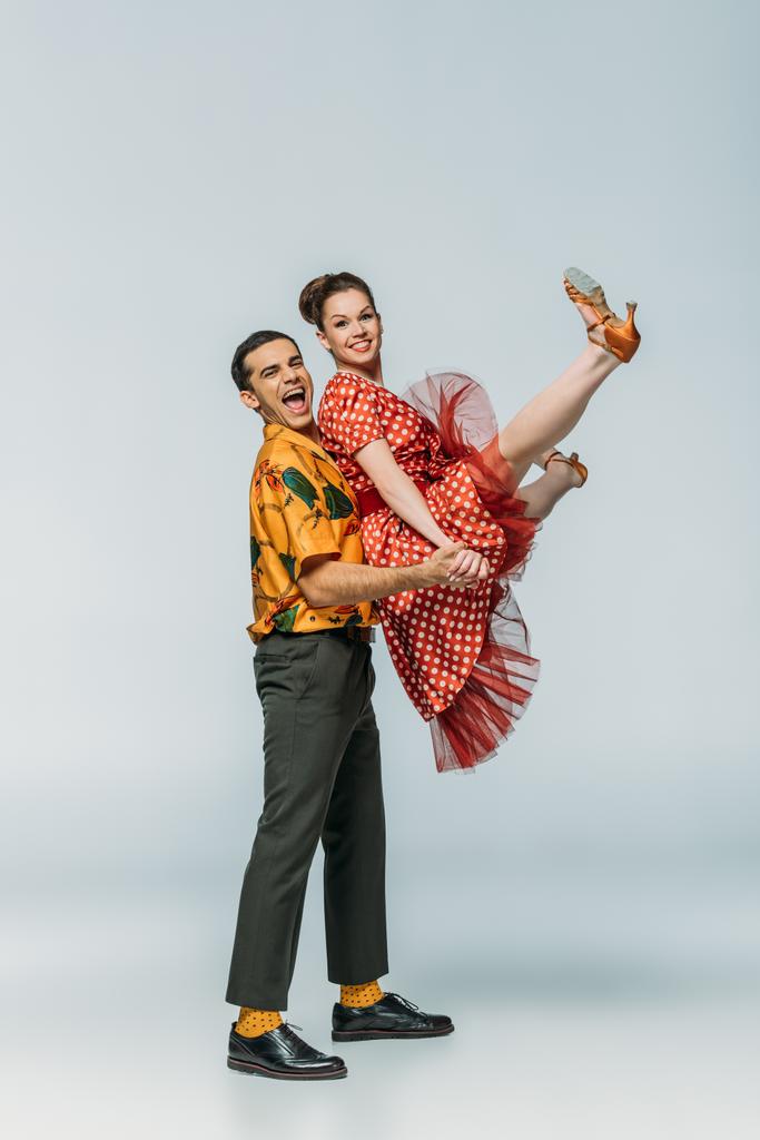 alegre dançarina segurando parceiro enquanto dança boogie-woogie no fundo cinza
 - Foto, Imagem
