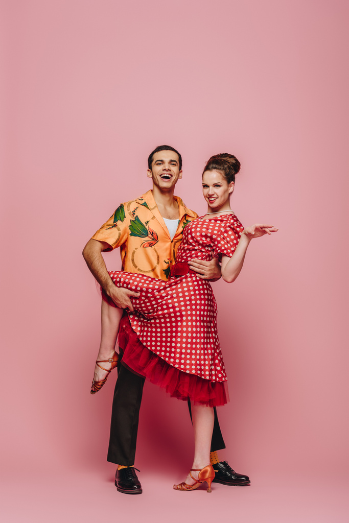 uśmiechnięty tancerz przytulanie partnera podczas tańca boogie-woogie na różowym tle - Zdjęcie, obraz