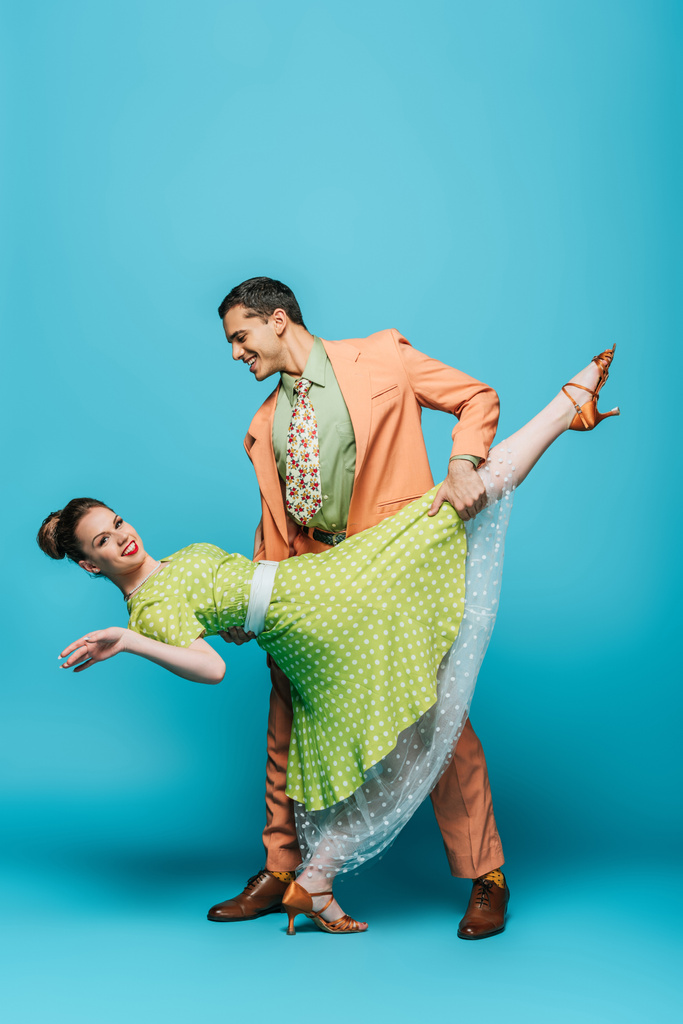 stijlvol danser ondersteuning meisje terwijl dansen boogie-woogie op blauwe achtergrond - Foto, afbeelding