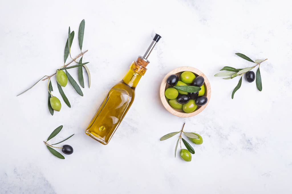 Creativo plano con botella de aceite de oliva, aceitunas y hojas
 - Foto, Imagen