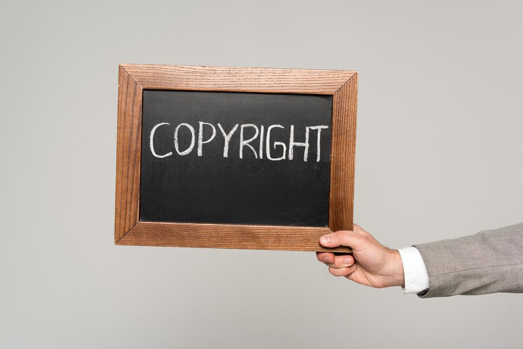 обрізаний вид бізнесмена, що тримає крейдяну дошку з авторським написом ізольовано на сірому
 - Фото, зображення