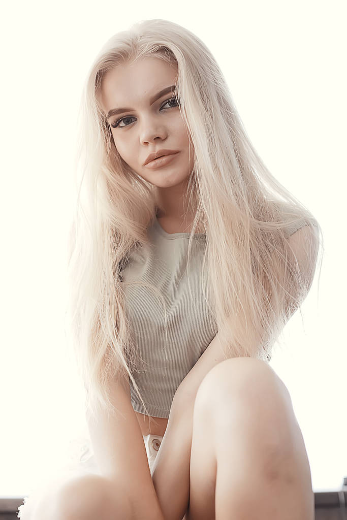 junge erwachsene blonde lange Haare zu Hause, stylisches Modell posiert im Studio - Foto, Bild